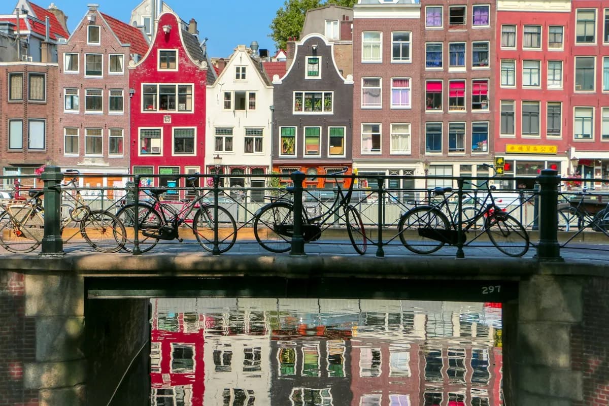 Bicycles on a canal bridge in front of colorful Amsterdam houses