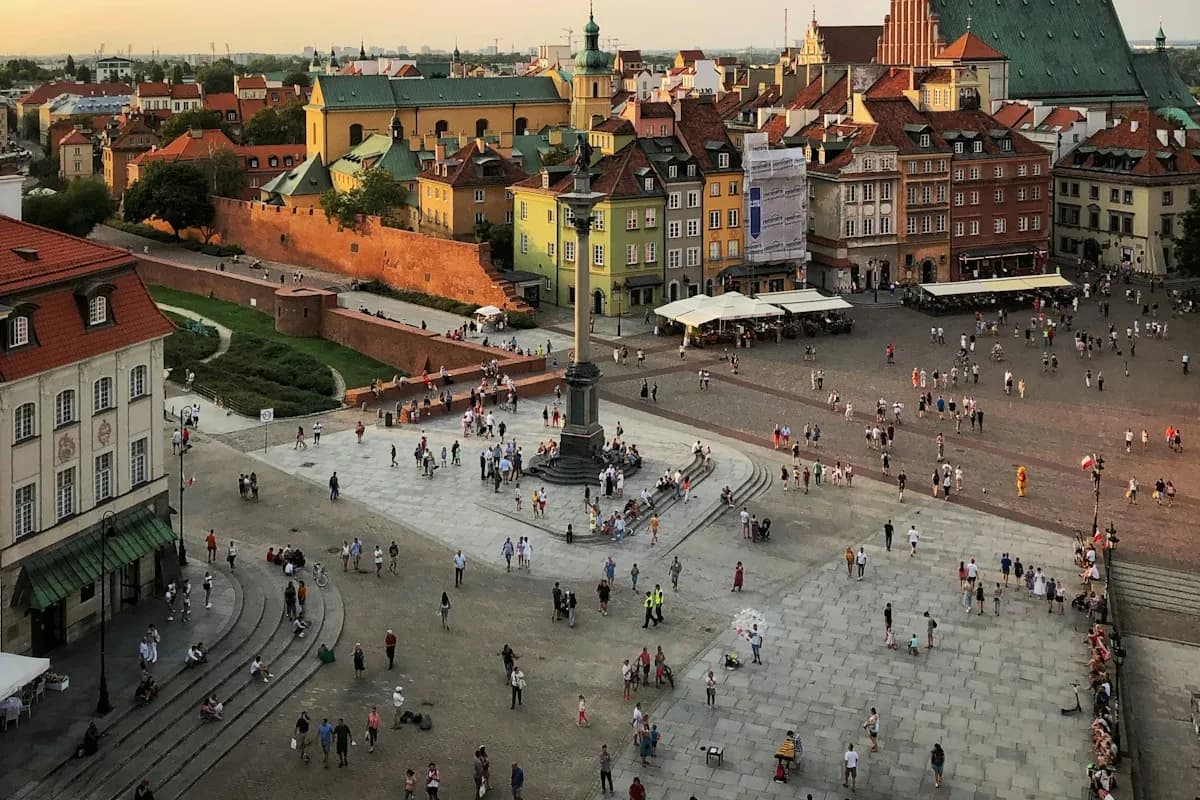 People crossing Castle Square beside Warsaw’s old-town buildings